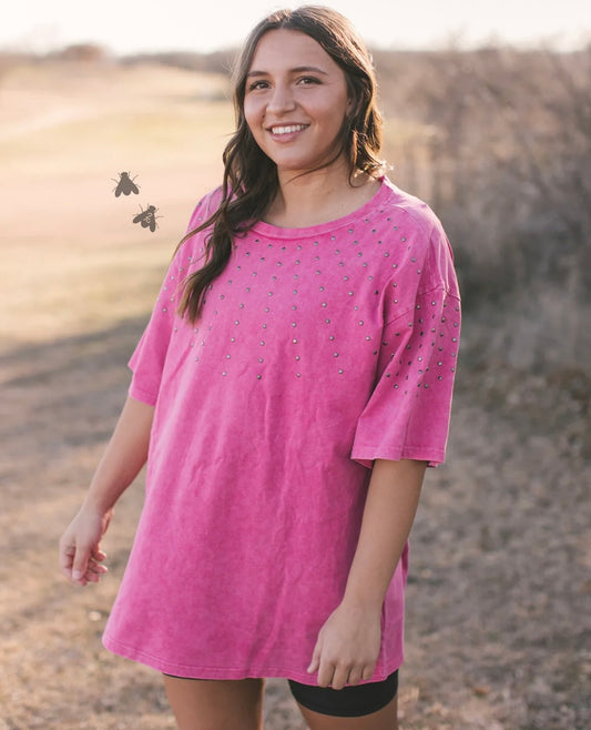 Woman wearing a pink dress with embellishments in an outdoor setting