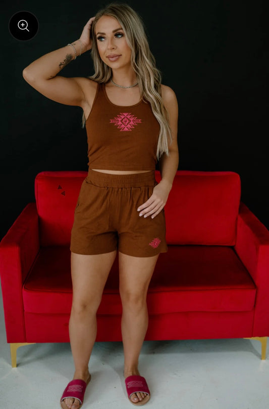 Woman wearing a brown outfit with a red couch in the background